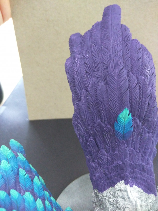 Now I start mixing my colors. The violet gets mixed with the Mediterranean Blue. I add some airbrush thinner to the mix. Not that I am using an aribrush, but it makes the paint more transparent. Then I glaze this color over the transition between the violet and blue on the feather, blending the colors a little bit. I blend the Mediterranean Blue with the Carribean Blue and do the same for the lower part of the feather. Lastly I thin some Graphene Grey with water, to an almost inky consistency, and draw a line down the middle of the feather. Lifting up the brush in the end, so it doesn't go all the way down.