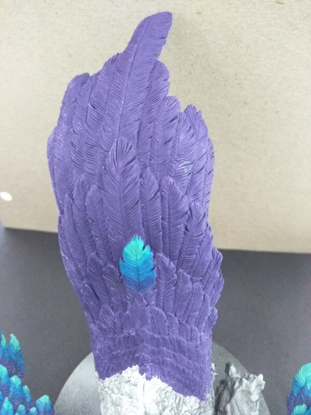 I then mix some of the Violet with the Creme White, and paint small lines on the Violet part of the feather, going halfway down the Violet and Blue mix on the feather. I repeat this with a mix of the Mediterrenean Blue and Creme White, going over the Blue area, and a bit down into the mix of the Mediterrenean Blue and Carribean Blue. And then finishing the last part of the feather with Carribean Blue and Creme White mixed together. The lighter you make these lines, the more contrast you'll get on your wings, giving depth to the thing.