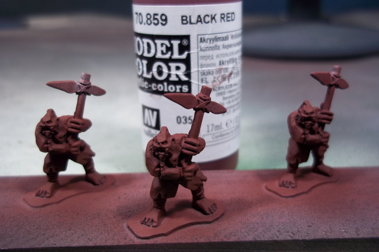 Basecoat - Vallejo Model Color Black Red applied with an airbrush.  Thin it to the consistency of milk and use a .35mm or larger needle/nozzle.  With practice and a large enough needle/nozzle, most non-airbrush paints can be airbrushed.  They're just a bit more tempermental.