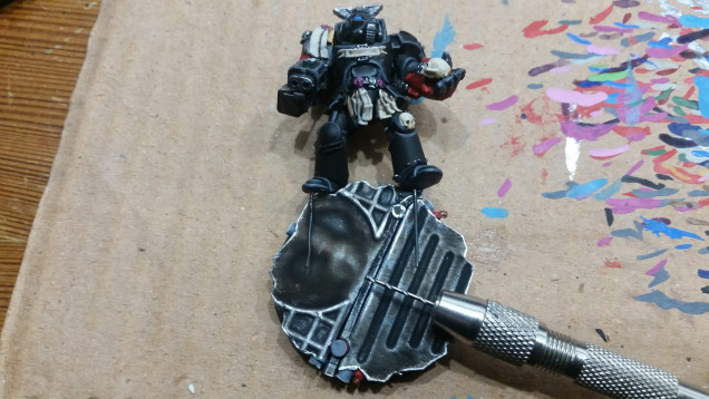 And here I am about to put one of the finished Terminators onto his base, by first drilling holes through it and the usind the wires in his feet to glue him onto the base.