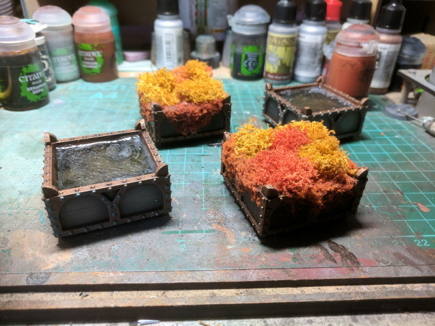 Painted up the boxes using standard dark metal and brass colours then added in the resin to a couple and glued the lichen into the others.