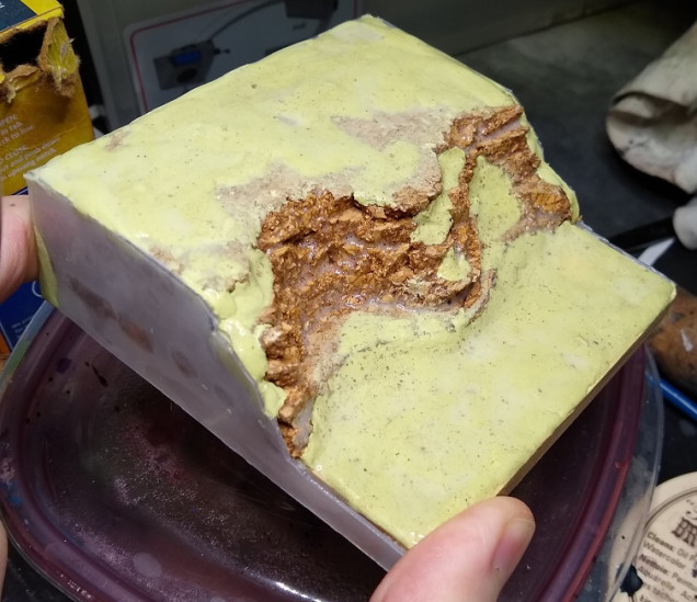 Then I added a bit of texture to some areas with a layer of miliput, and glued some plastic I'd cut out to the sides of the base to create a flat edge. In this picture it's glistening with watered down PVA glue in preparation for the next step.