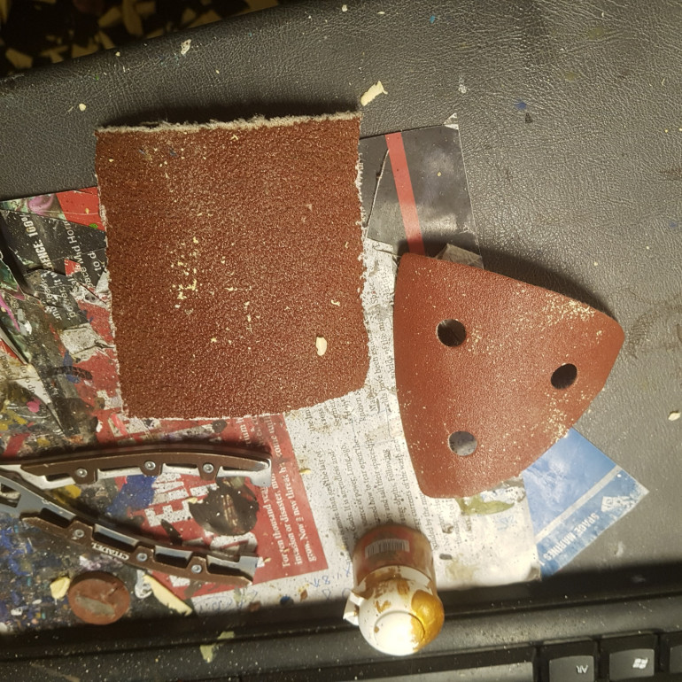 Two Different Grades of Sandpaper. The Triangular One is for an Orbital Sander and the Larger is a Belt Sander Belt Cut to Size.