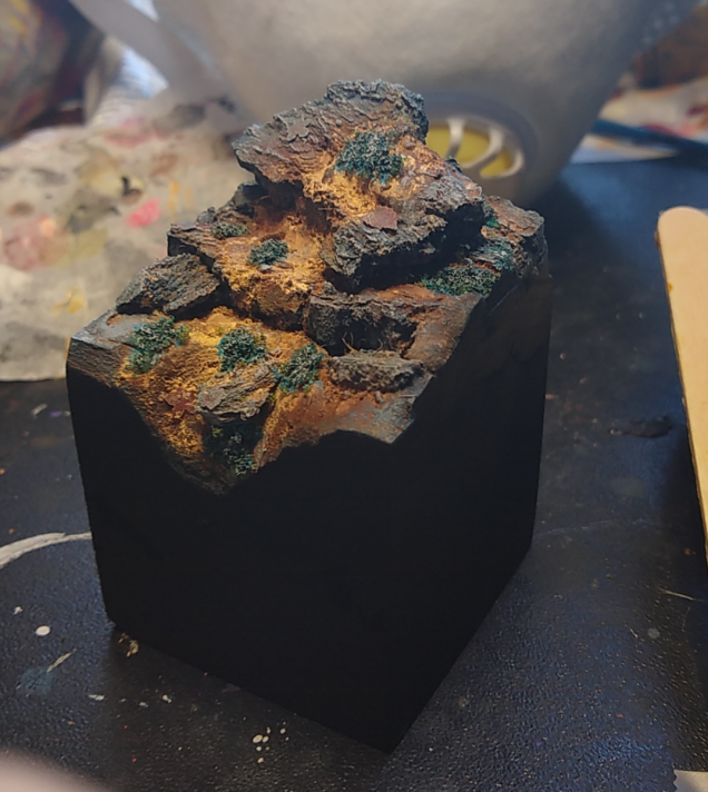 I used some fine clump flock soaked in super glue, painted with bluegreen ink, and then drybrushed with grey to create some moss/lichenish vegetation.