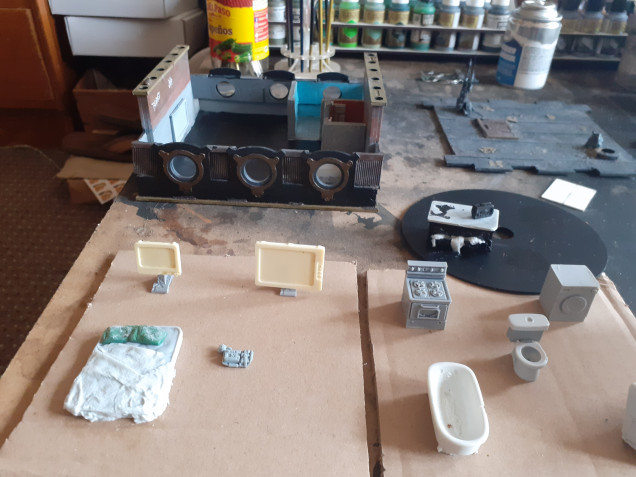 I have basecoated the interior of the building and glued all the furniture onto cardboard ready for spraying. I then sculpted two pillows and used some very valuable toilet paper soaked in pva glue to make the sheets and clothes hanging out of draw.