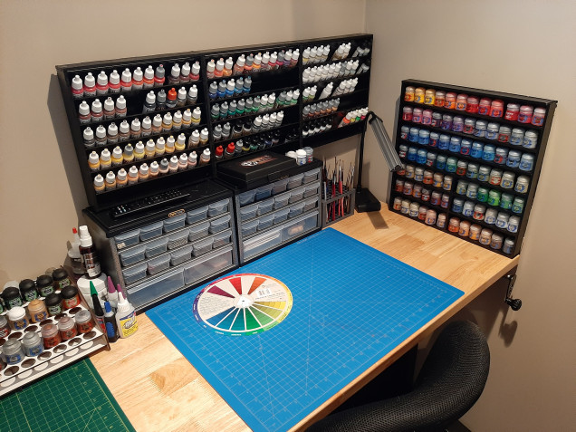 Homemade paint rack for pots.  Dropper bottles up with racks from Hobbyzone sprayed black.  They are all mounted to the table instead of the wall for easy removal or rearrange down the road.  Storage containers are little cheap units from the DIY store.  Paint brush holder is a unit from Amazon and some new cut mats from there as well. Tip: I'm not sure where I got this from but, if you rack your dropper bottle paints and want a better visual of the color, put a drop on the cap and it will give you a better sense of the color and make it easier to find. Almost there just a few finishing touches to finish up.