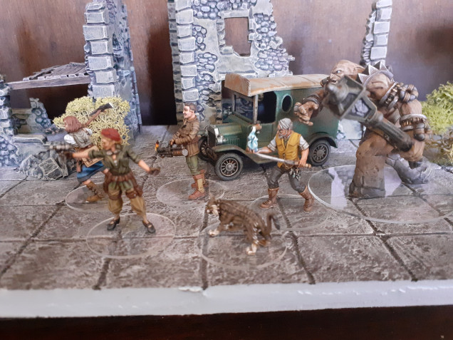 The miniatures displayed with some of the scenery I painted whilst waiting for my first order of Mythos models to arrive. The buildings are the Warlord plastic hamlet models and the van is a Lledo Walkers crisps promo model repainted. 