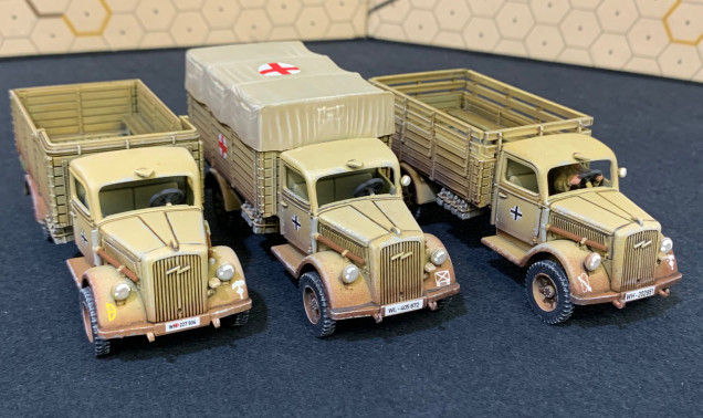 Markings are for (left to right) 21st Panzer Division, generic motorized infantry for the medic truck, and 90th Light Division for the truck on the right.