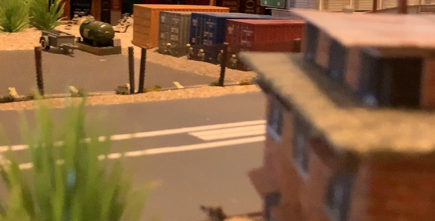 Marine at lower center (close up, out of focus), spots Iraqi infantry by the containers, and armor as well.  Time to call in the M777s with the Dual-Purpose Improved Conventional Munitions (DPICM) artillery and maybe some Copperhead ATGWs!