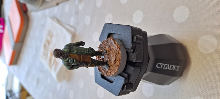 Once the figure is painted I use Vallejo Texture Paints Brown Earth to create the texture for the base.  The Citadel Hobby Texture thing is used for spreading this out.  I give this a wash with Dark Tone from the Army Painter.