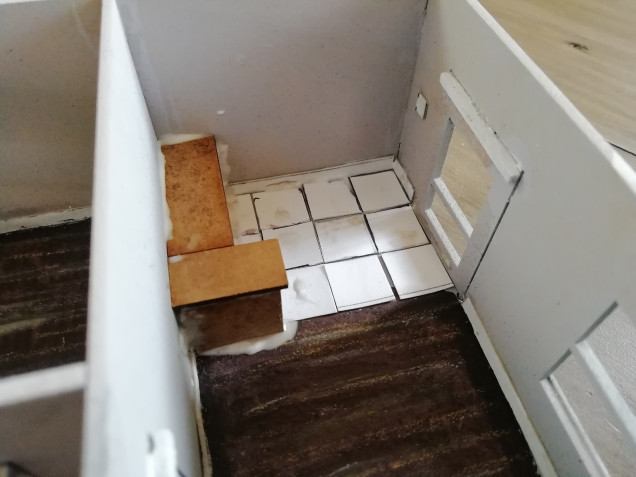 Work begins on the interior of one building. I've painted the floor and used crayons to draw in wood boards. I've built a little kitchen and tiled the floor with card