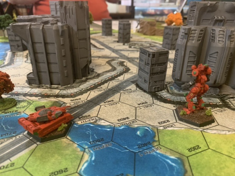 On the other flank, a Rommel trundles forward over a bridge while the Hatchetman uses its jump jets to sail over the city wall and take cover behind a building. 