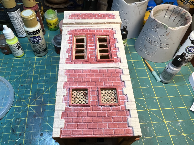 Bricks were painted on a sand primer using a red brick town from a craft paint brand (Heritage Brick from Americana). Mortar was obtained by applying  an off-white thin out layer of paint over the dry brick color and promptly wiping it off with a paper towel. Not perfect, but good enough from a table perspective. The stone was painted using light beige paint which was them washed with a home made wash of brown/black craft paint mixed with a few drops of dishwashing liquid and water. Again, there are better recipes online but this one works for  my terrain.