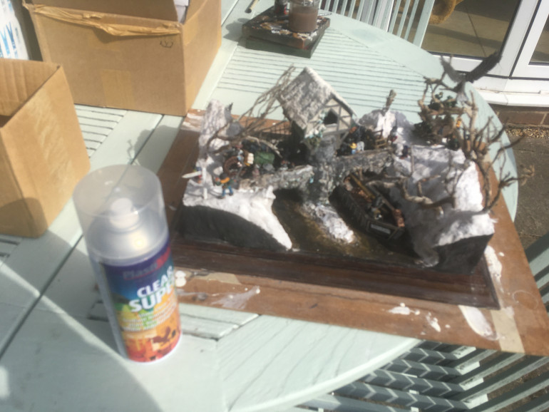 To protect the miniatures better this time, the whole diorama has been sprayed with Gloss Clear PlastiKote. The plaster and paint will protect the polystyrene superstructure which normally melt if sprayed and the gloss will give a fresh glint to the wood display base. 