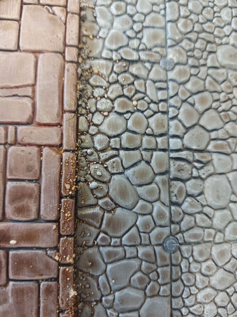 I always love my fiddly little details, so I also added some small rock scatter to the street panels, to give them a more worn look. I painted, inked, and drybrushed them to match either the street or the footpath. 