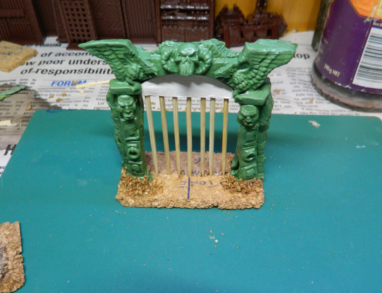 I added a piece of card on each side at the top to fill in the gap there, roughed up the edges of the tile to blend into the table better and used the resultant cork rubble to blend the archway into the base.