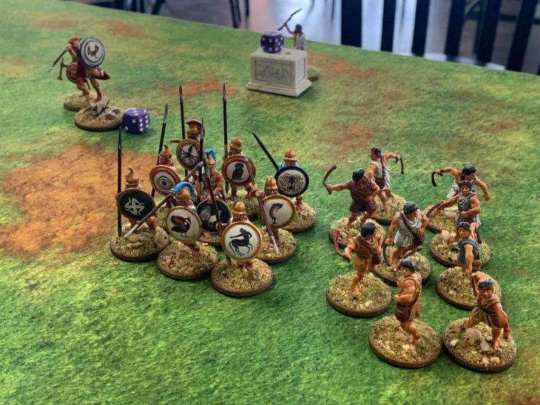 TimToo watches the battle from his shrine. Bradicles brushes an imaginary speck of dust off his breastplate. The Hoplites form up and the slingers ready their shots.