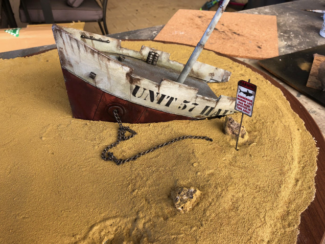 I painted the sand in regular household paint. Then I made a simple sign from copper sheet and a copper wire.  The sign is a decal I printed off at home.  This was weathered to look old.  I added streaks of weathering to the ship and glued it in place.  Next I added some chains.