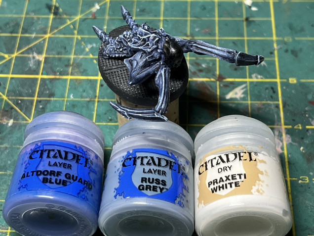 Once dry, the body received three progressive drybrush layers of GW Altdorf Guard Blue, GW Russ Grey and GW Dry Praxeti White, in progressively smaller and more light-exposed areas.