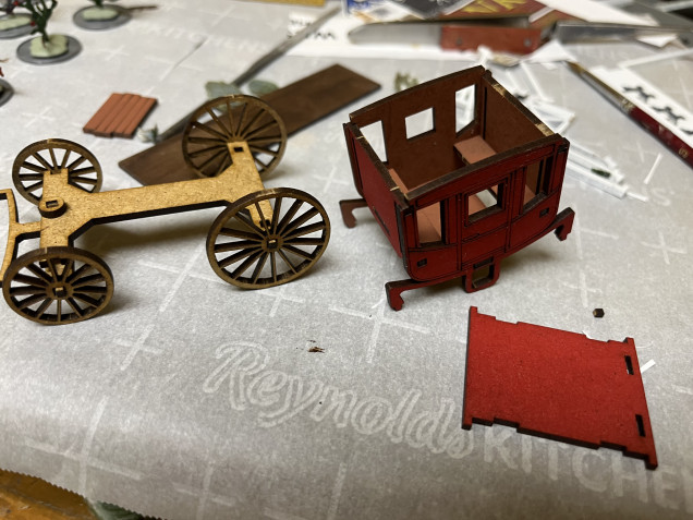 Stage coach in three parts, undercarriage, body and roof. I used Army Painter Fur Brown for the interior and Dragon Red for the exterior of the body. Both were sprayed on while the parts were still on the MDF sprue. 