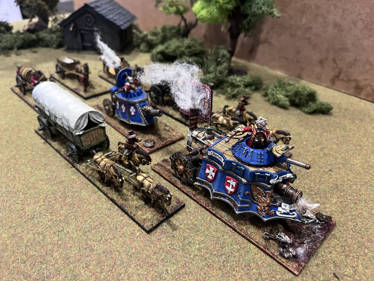 The steam tanks head out with wagon train in support. I’m particularly pleased with the smoke and the cannister shotte casualties on the main tanks base. The casualty is one miniature cut in half and the two sides used as two corpses. The models stand too proud of the ground if they aren’t reduced like this.
