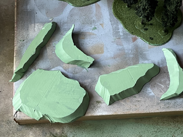 I cut up some foam with a wire foam cutter to make some hills and mesas.  I then used a green acrylic primer on them.  I probably should have filled in the precut lines before priming.  