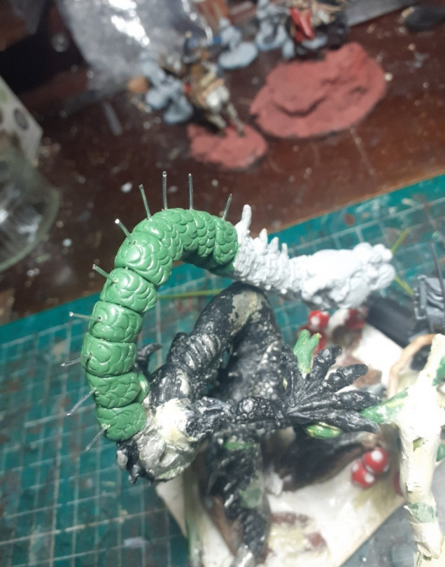 It was then a matter of building up the neck with green stuff and trying to make it match the rest of the model. The scales were formed using the end of a paintbrush cover pushed I at an angle, the wires were added to build the spines around