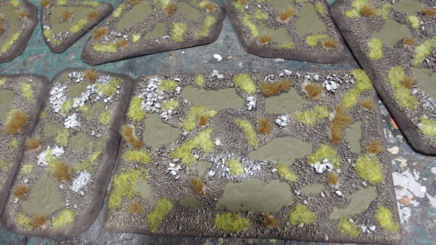 Using PVA glue first apply green static grass to the model and the using PVA glue apply dead grass tufts. Spread both of these around and don't clutter the piece.