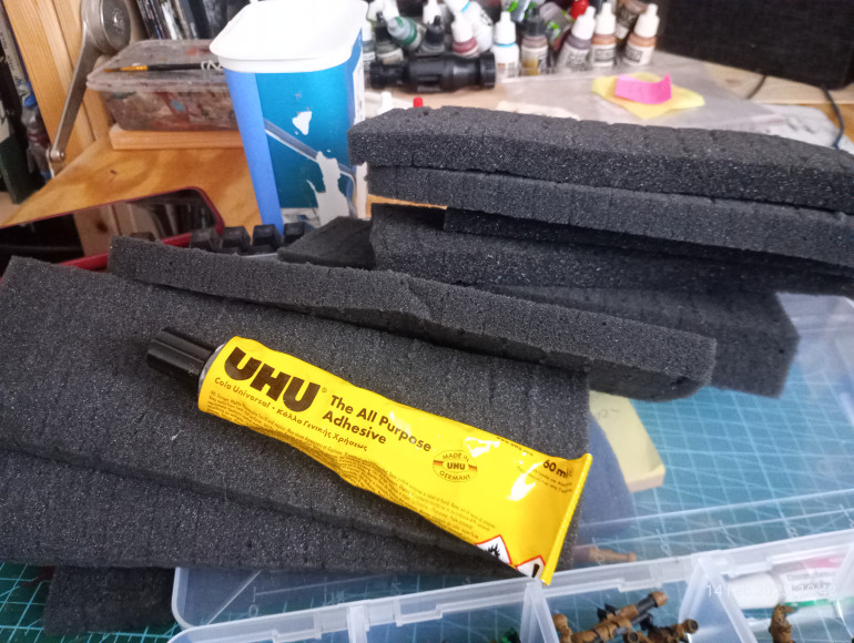 Foam and any all purpose glue will do. I used different foams from all deliveries I had over last few months. I kept them for move we had but now with storage capacity we have I will keep all for storage and terrain builds.