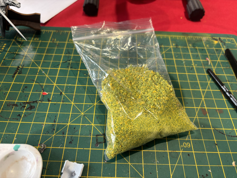 Now on the card the model has flowers on his cloak, I tried painting them in but they looked weird so I scrubbed them and decided on a different approach. I found a bag of flock which had yellow bits in it and decided to glue them on directly.