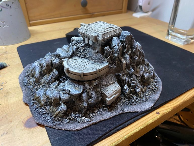 Assembled and primed - uses sci-fi fleet battle asteroid / space station terrain sized, cut and blended into rock outcrops and 3d printed. Once printed, mounted on masonite board and based with various gravel / sand types. Aim is to have buildings etc. blend into the gaming table more than a typical cube building would.