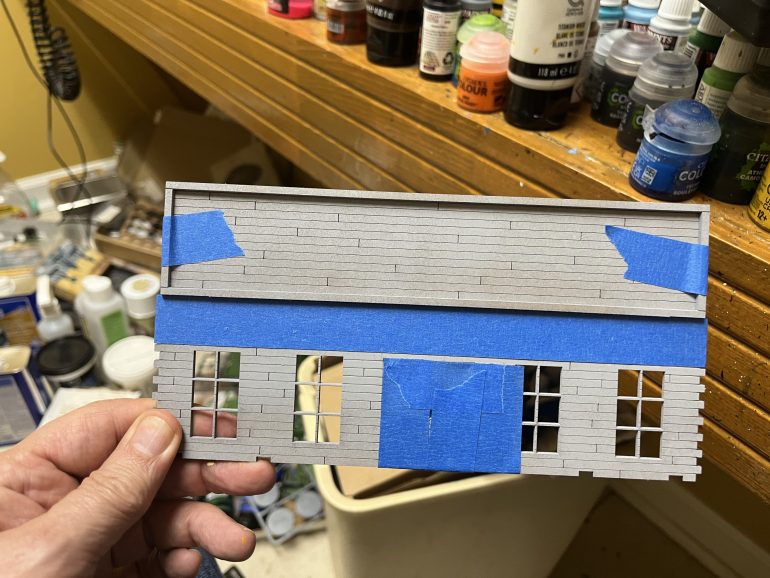 I masked off the front doors and used masking tape to hold the sign frame in place. Everything in the frame will be painted black. The horizontal piece of tape marks the edge of the frame.