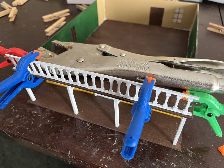 Here I’m starting to add the railings to the deck. I had to clamp them in place to keep them from falling over. I used the adjustable wrench as a weight to make sure the upper deck fit snugly onto the supports.