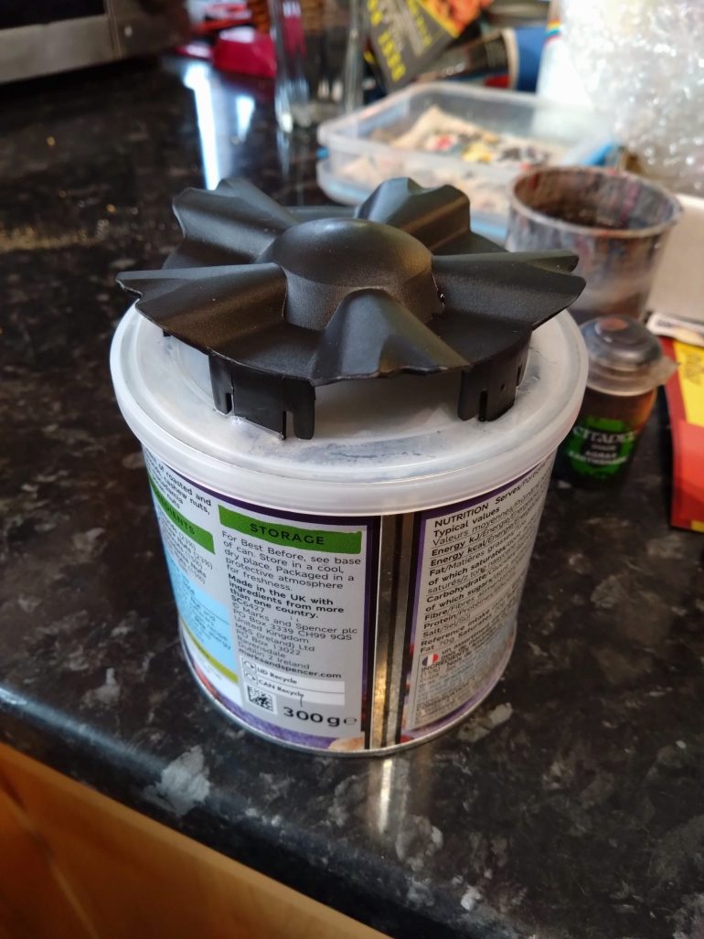 The top piece fitted into the peanut tub lid once I made some marks and craft knife cuts for the grommet's own clipping points to push through.