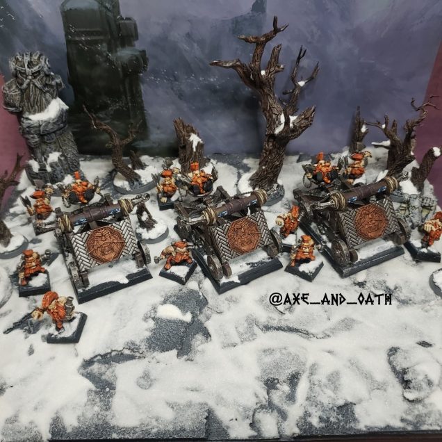 Scenic Warhammer The Old World photograph of Dwarf Slayer Doom Seeker Divers positioned on a snowy mountainside. Three converted Grudge Thrower war machines crewed by Doomseekers and Slayer Engineers stand among snow-covered trees, with a vast mountain pass in the distance. Harsh winter weather, swirling snow, and strong winds create a bleak Karak Kadrin alpine battlefield atmosphere inspired by Warhammer Fantasy and the Gotrek and Felix novels.