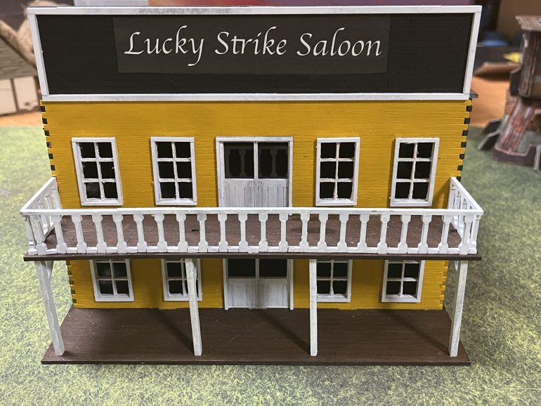 I found a suitable font, and printed it on a black background then cut to size and used PVA glue to affix to the billboard.  