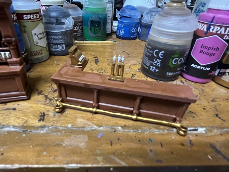 Knuckle Duster miniatures makes resin and metal bar furniture. The resin needed some sanding and the footrests needed some straightening but otherwise was pretty easy to assemble.  Base coated Army Painter Fur Brown then bottles and brass painted using a variety of colors. Then everything given a wash of Army Painter Soft Tone. 