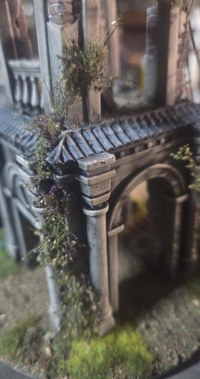 On another corner I added ivy, tearing apart a long stem purple flowered shrub, removing most of the purple.Then with a puddle of superglue, pick each piece with tweezers, gently squish on side of stem in puddle the apply to building, working from ground upwards. Pictures of completed model to follow. On another corner I used lichen on a similar way only in larger chunks.