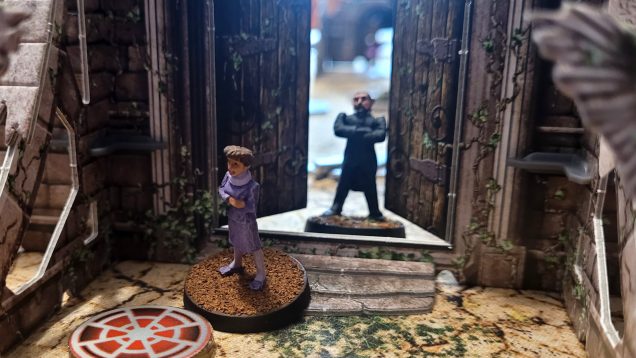 The '80s Master menaces Tegan from behind a very on-brand cardboard door...