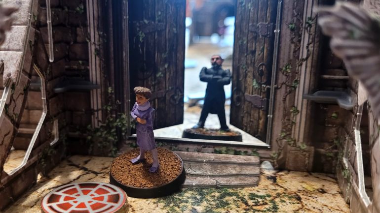 The '80s Master menaces Tegan from behind a very on-brand cardboard door...