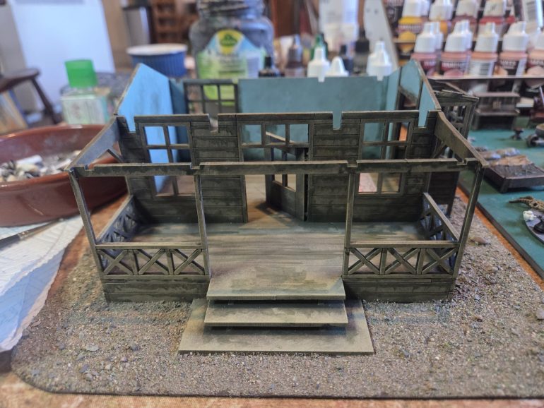 I have drybrushed all internal walls upto a pale blue. On the exterior I have used a green wash to add weathering and delineation of all the planks of wood