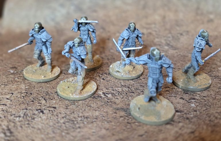 The Good Guys. Undercoated, drybrushed up in a khaki/grey mix, adding Warpaints (WP) Brainmater Beige until I was happy. Painted the visors in WP Tainted Garden and adding Brainmatter Beige (BB), with a final dot of almost pure BB. I then added sand to the base, when this dried I dusted the two pigments generously over the base and more sparingly up the lower half of their legs. I finished off as described above.