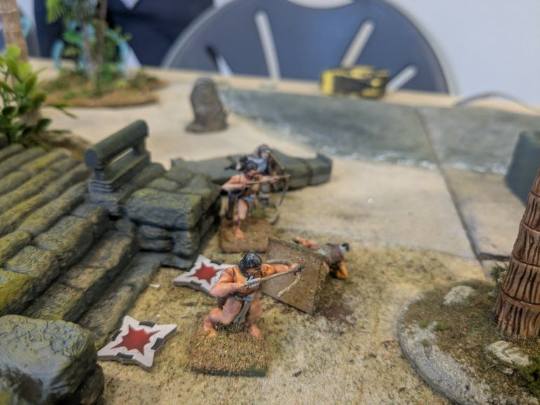 Ammunition amy blasts away with her Tommy gun but received an arrow in the neck in return and bleeds out on the beach