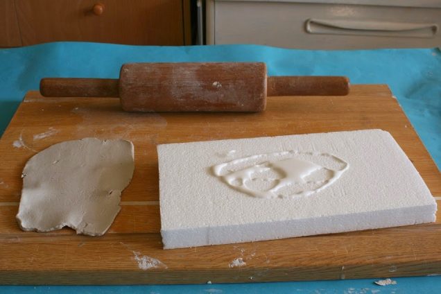 Rolling out the clay into a thin layer and gluing it on to the polystyrene.