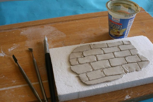 While still wet, cut in the shape of the bricks into the wall.