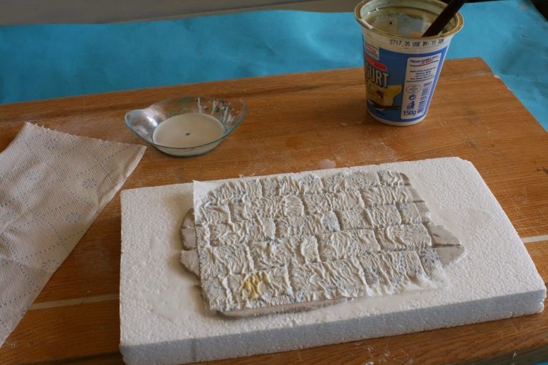 The last step is to wet the bricks with diluted PVA glue and place tissue over it. Use an old brush to push and fit the tissue into the brick's crevices.  Use more diluted on top of the tissue if necessary.  This should give you a nice stoney tecture when dry.